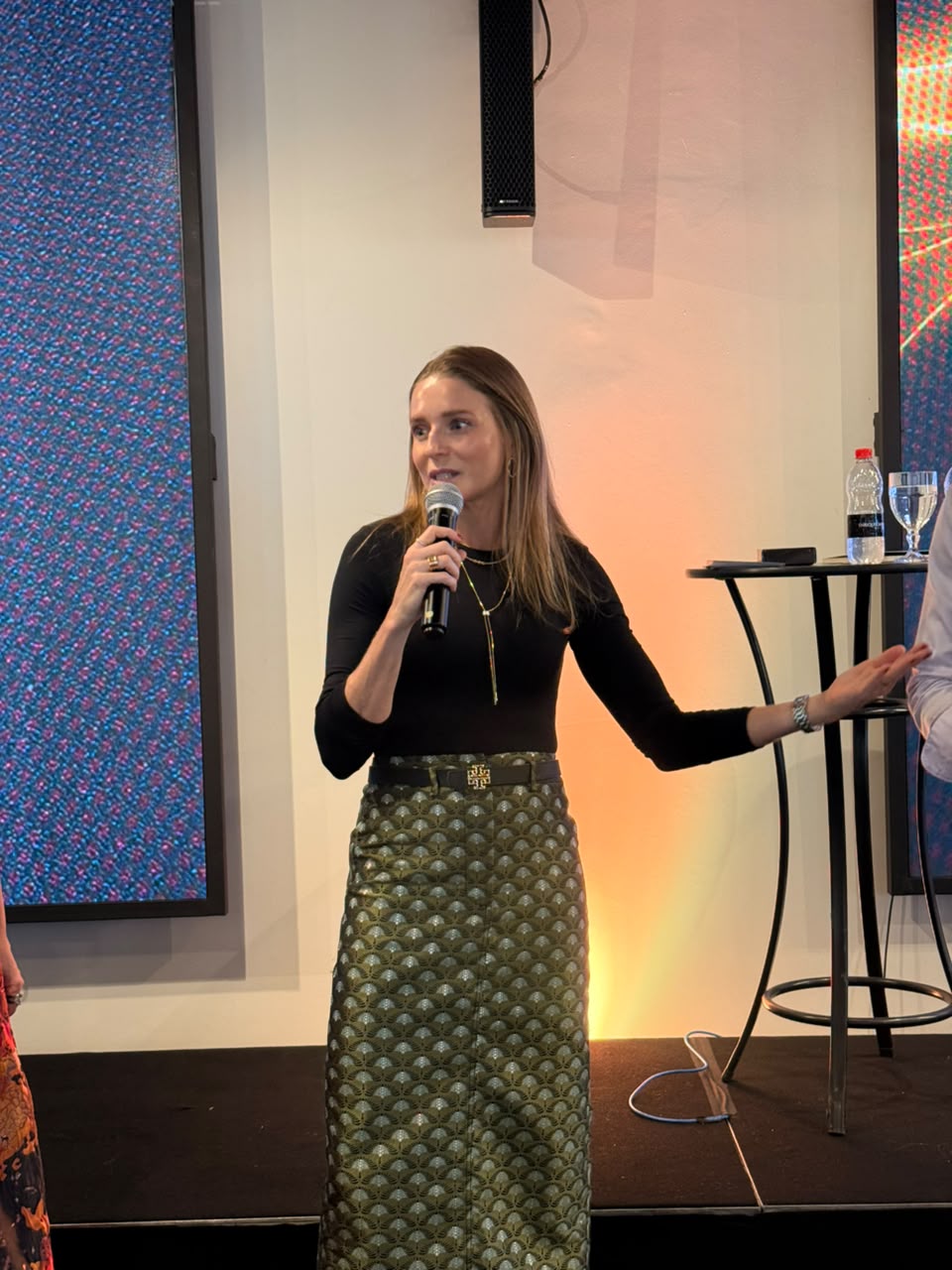 Camila Mariano palestrando com microfone em evento